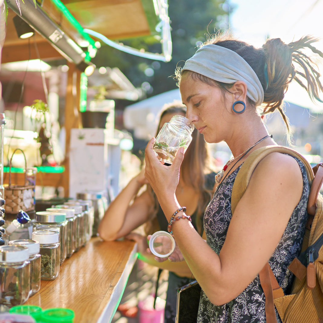 Women at a market stall smelling cannabis in a jar