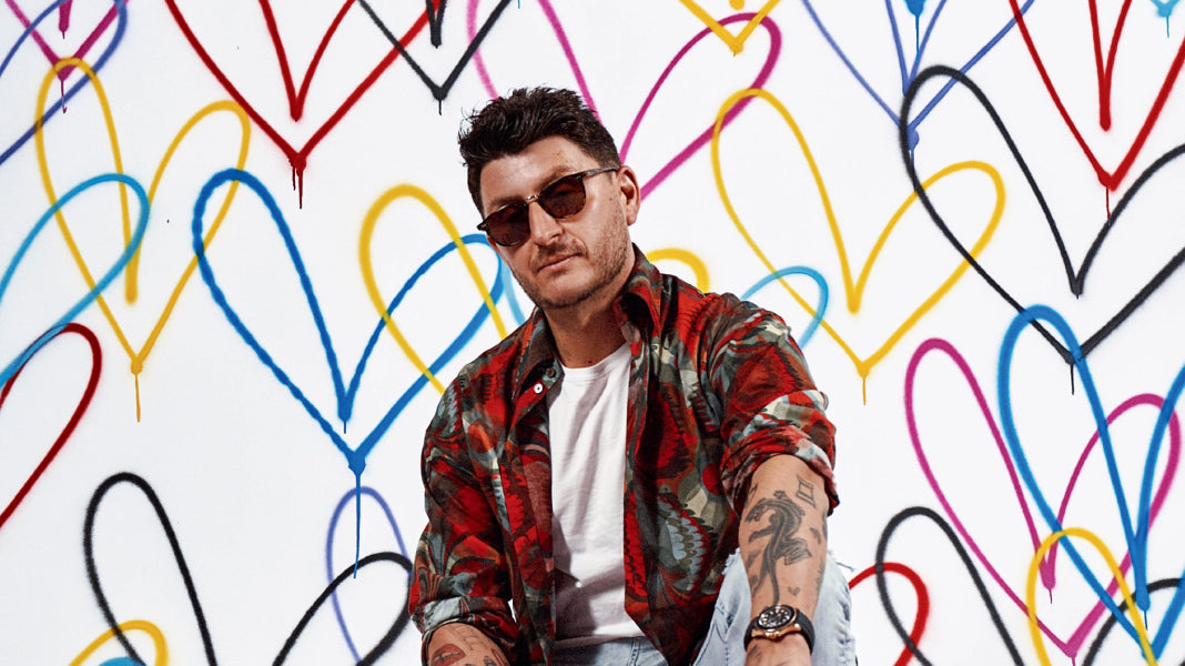 JGoldcrown sitting in front of his heart artwork