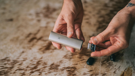 Hands holding a silver PAX Pod