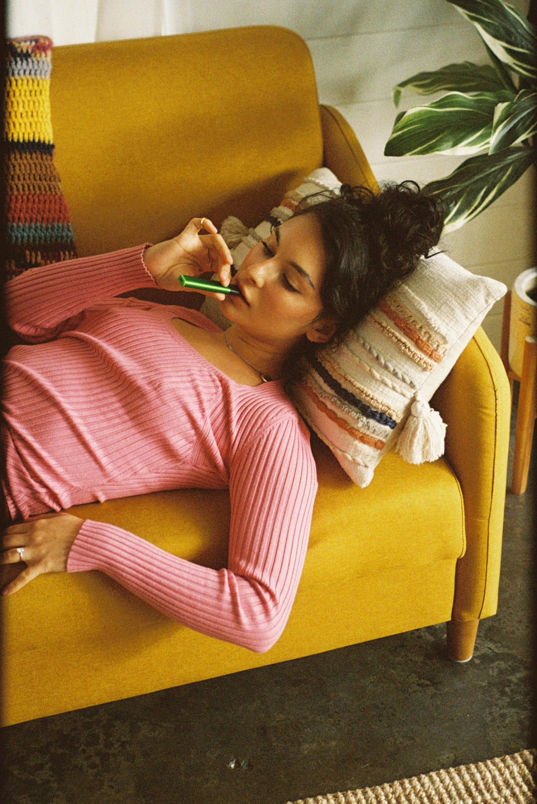 Woman using her PAX vape pen while laying on the couch