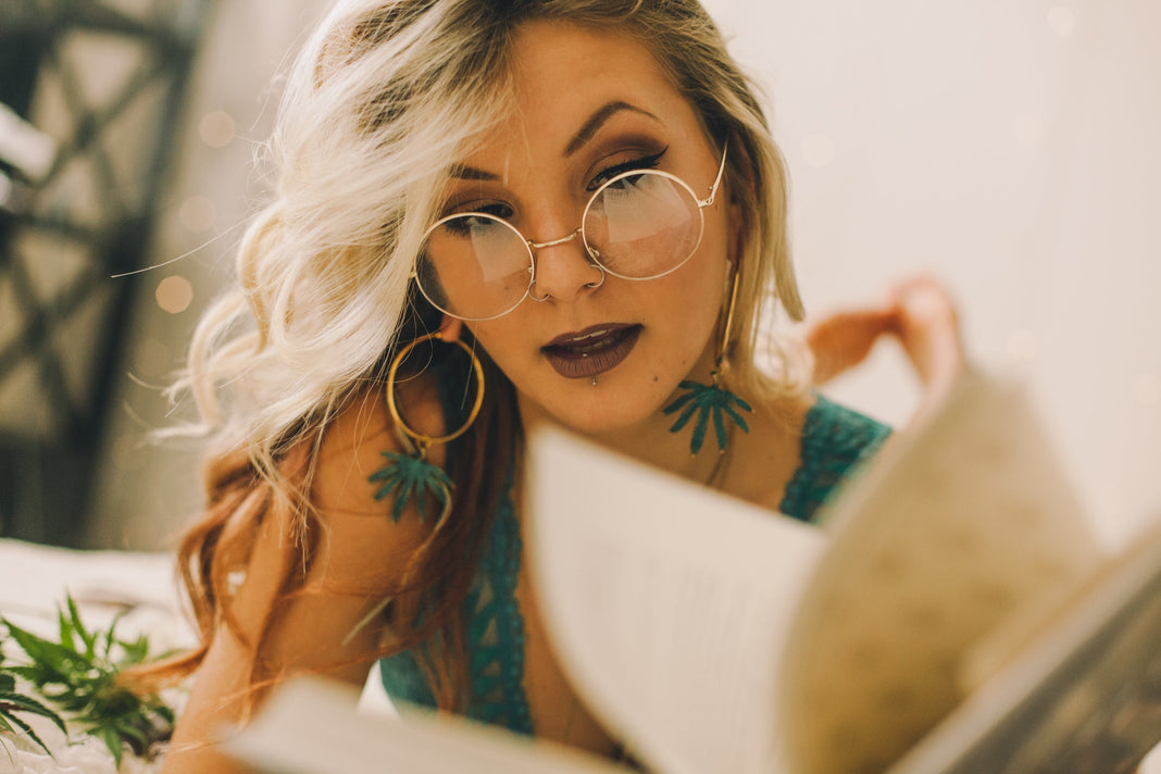 Woman with cannabis leaf earrings reading a book